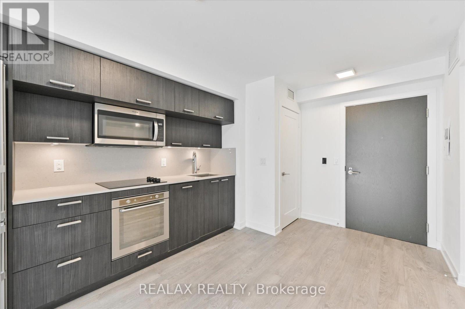 A modern kitchen with dark wood cabinets and a stainless steel microwave.