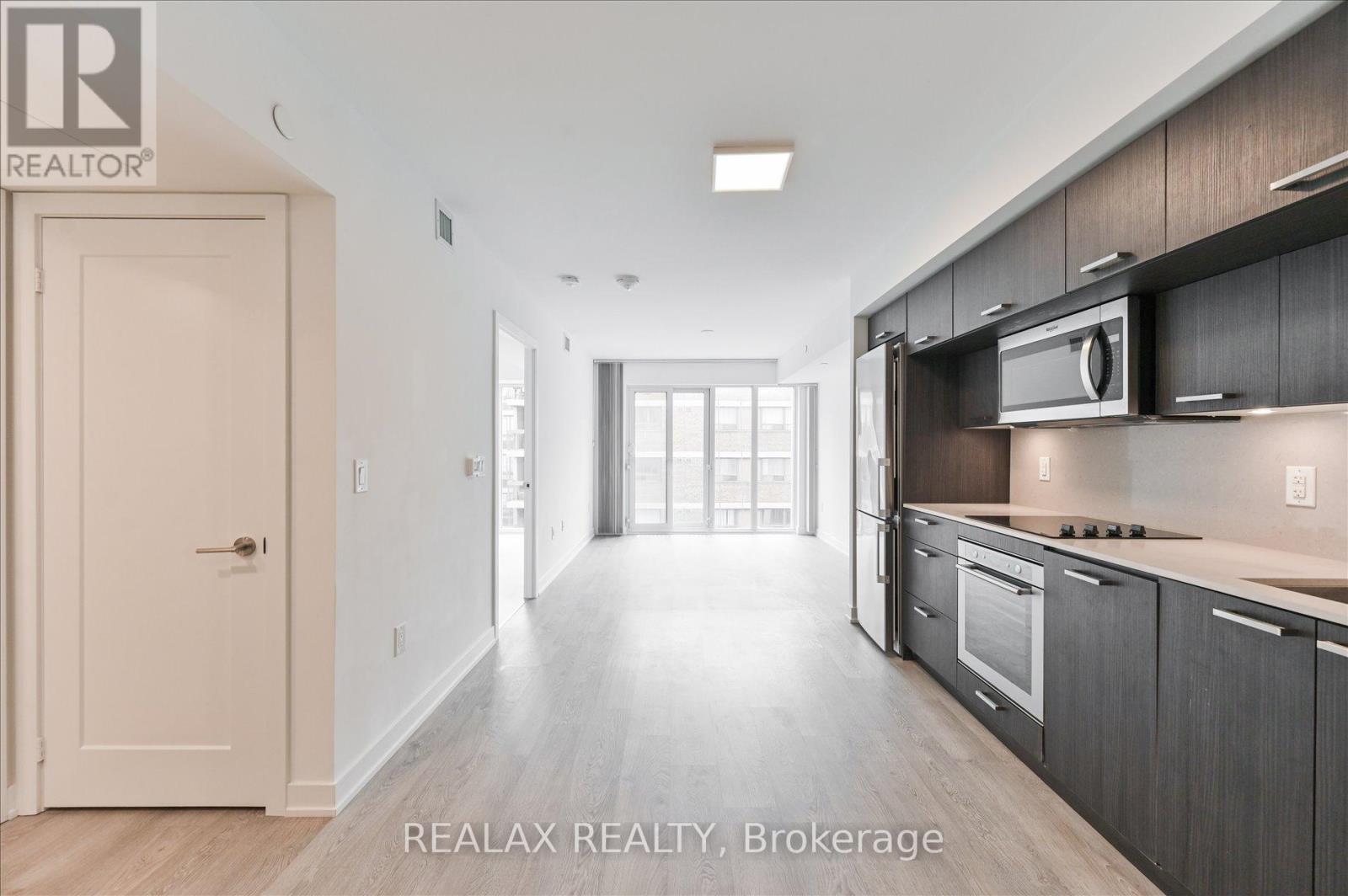 A modern kitchen with dark wood cabinets and stainless steel appliances.