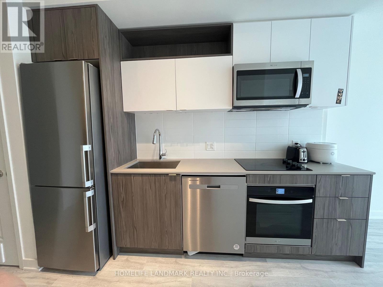 A modern kitchen with a stainless steel refrigerator, microwave, and oven.