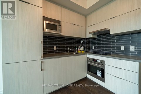 A modern kitchen with white cabinets and a black tile backsplash.