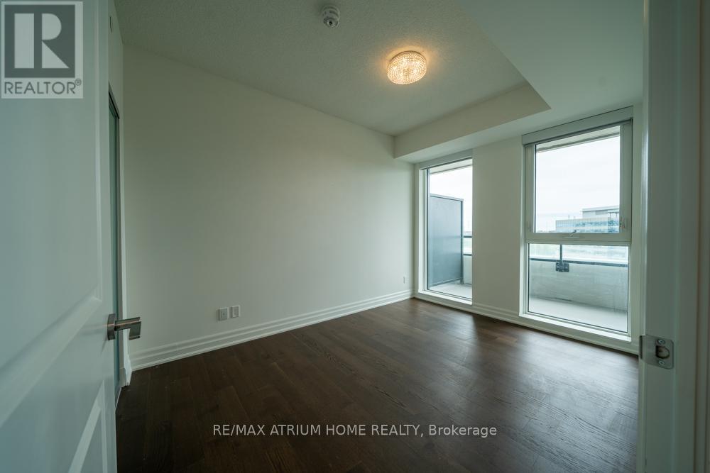 A room with a wooden floor and a window overlooking a parking lot.