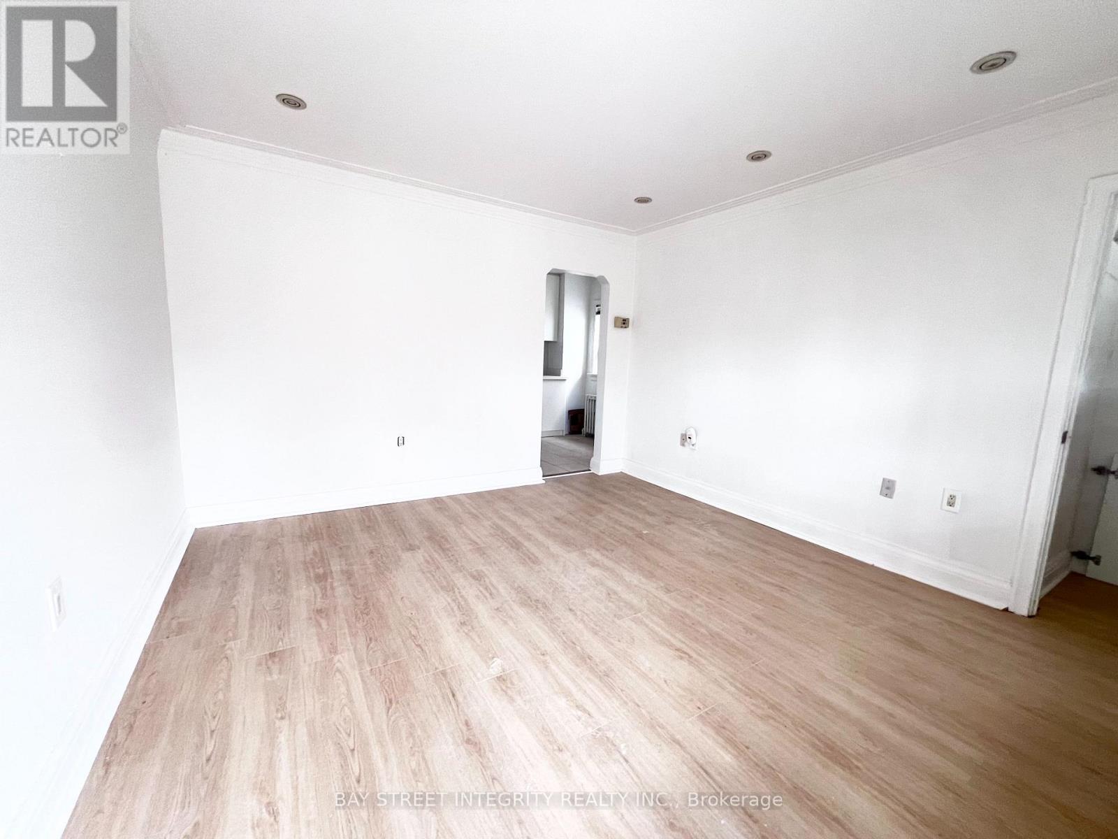 A spacious room with wooden flooring and white walls.