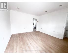 A spacious room with wooden flooring and white walls.
