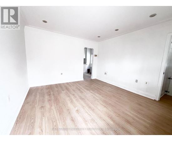 A spacious room with wooden flooring and white walls.