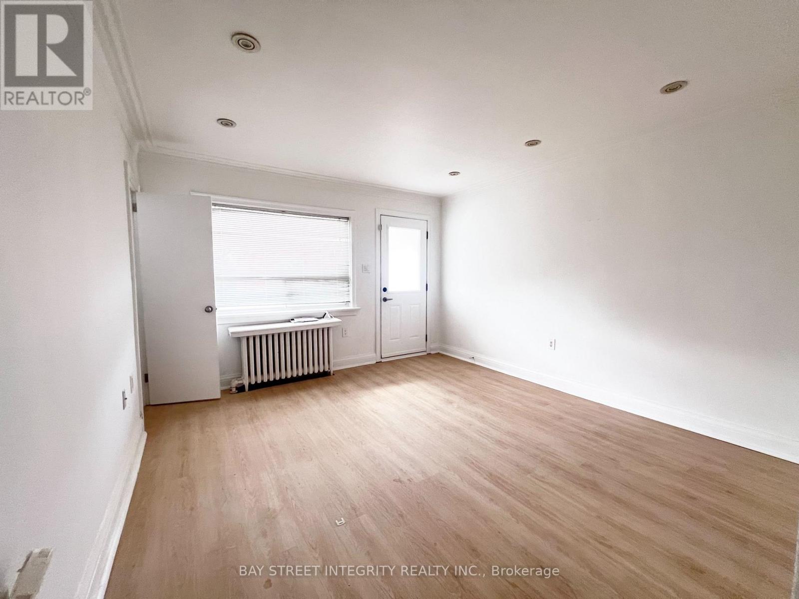A room with a window and a door is empty and waiting to be furnished.