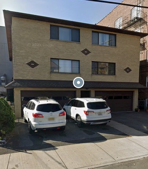 Two white cars are parked in front of a two-story building.
