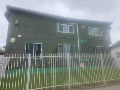 A green building with a white fence in front.