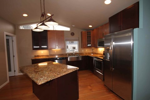 A kitchen with a granite counter top and stainless steel appliances.
