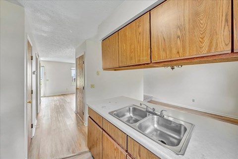 A kitchen with wooden cabinets and a stainless steel sink.