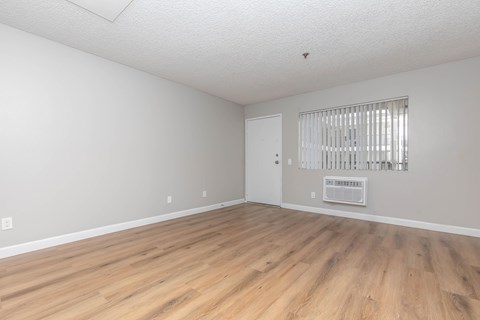Empty room with wooden flooring and white walls.