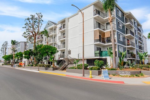 A street view of a multi-story residential building with balconies and a sign that reads "Gateway".