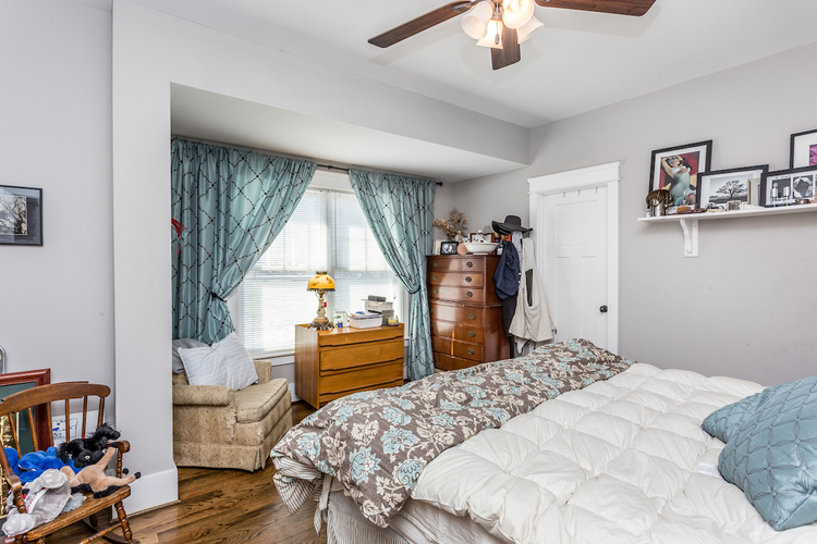 A bedroom with a white bed and a window with blue curtains.