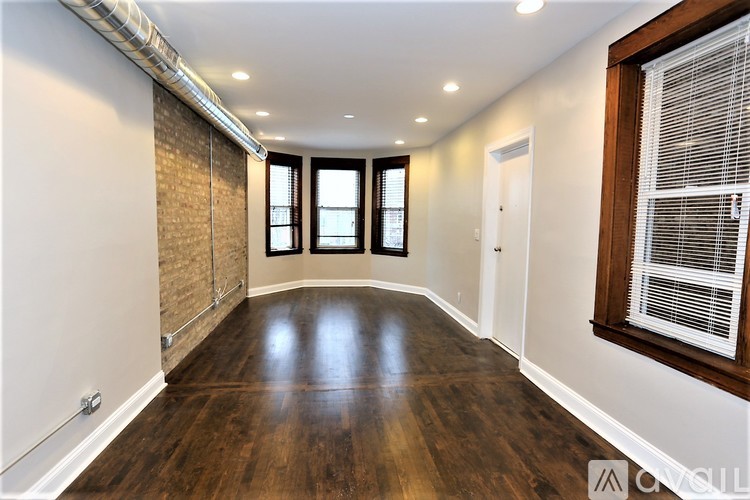 A room with wooden floors and a window with blinds.