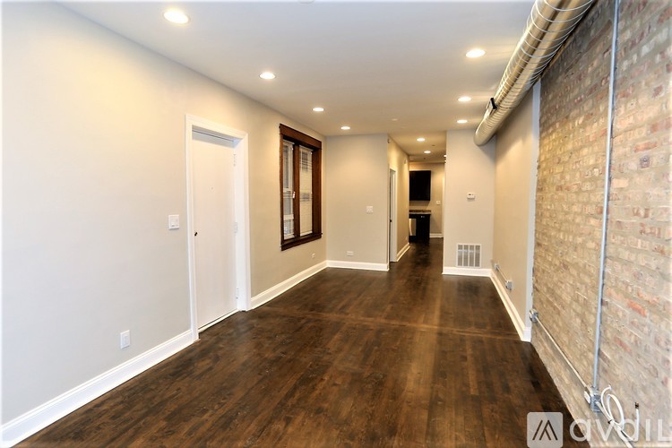 A long hallway with wood floors and white walls.