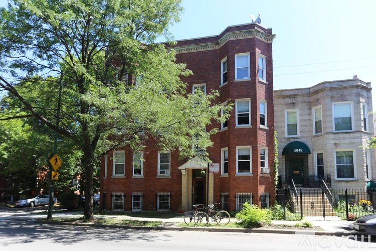 A red brick building with a tree in front of it.
