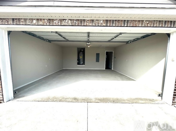 A white garage door is open, revealing a clean, empty garage inside.