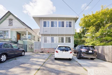 A white two-story house with a car parked in front.
