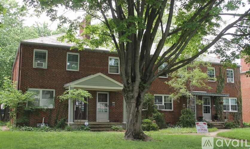 A red brick house with a tree in front.