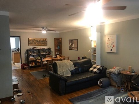 A living room with a black couch and a ceiling fan.