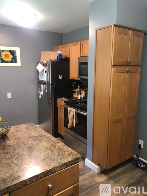 A kitchen with a black fridge and wooden cabinets.
