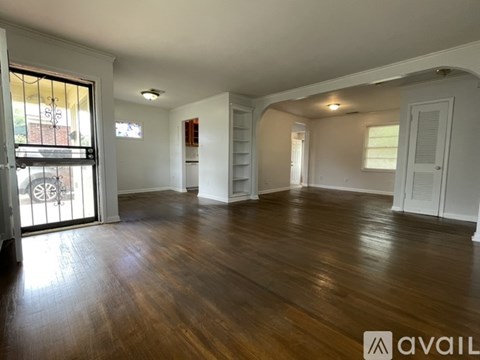 A spacious room with wooden floors and white walls.