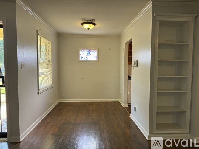 A room with wooden floors and white walls, with a door leading outside.