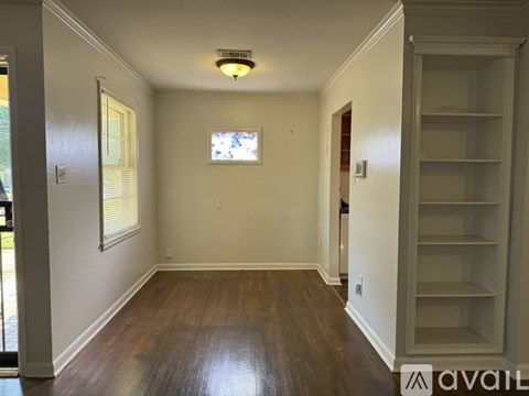 A room with wooden floors and white walls, with a door leading outside.