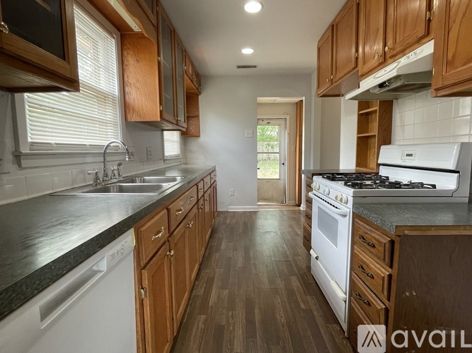 A kitchen with wooden cabinets and a white stove top oven.