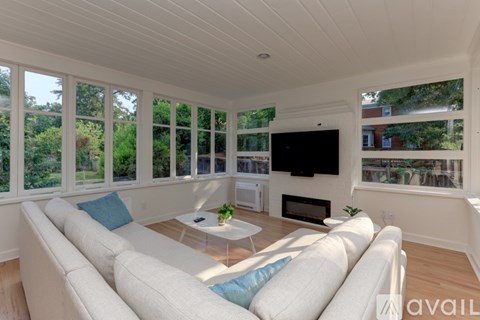 A sunny day in a living room with a white couch and a television.
