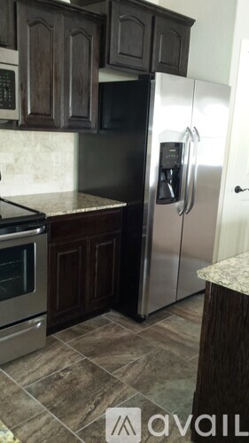 A kitchen with a black fridge and wooden cabinets.