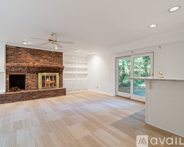 A spacious room with a brick fireplace and wooden flooring.