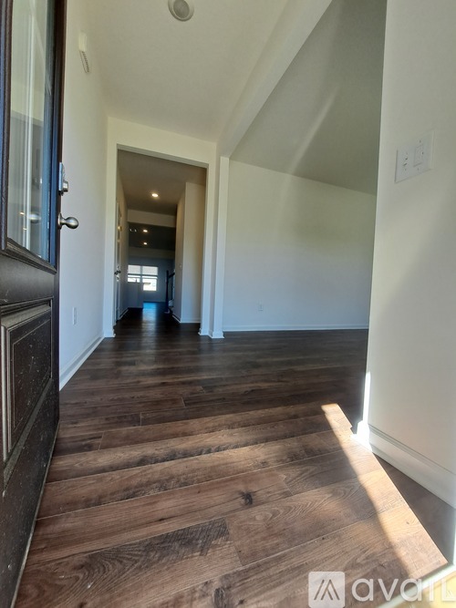 A hallway with wooden floors and white walls.