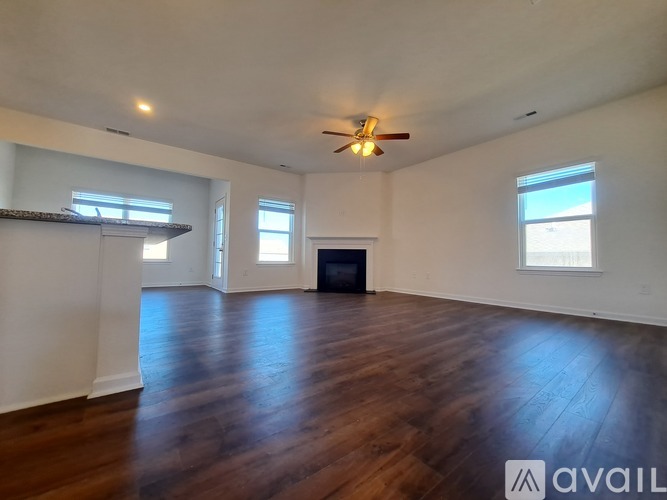 A spacious room with wooden floors and a fireplace.