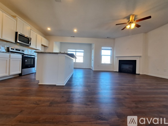A spacious kitchen with white cabinets and a dark wood floor.