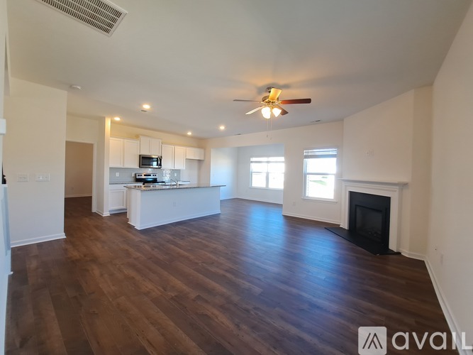 A spacious living room with wood flooring and a fireplace.