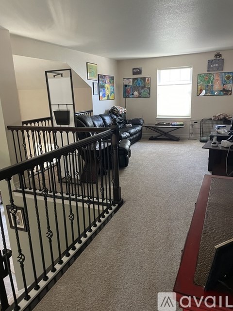 A living room with a black couch and a staircase with a railing.