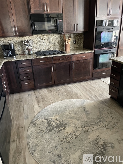 A kitchen with brown cabinets and a granite countertop.