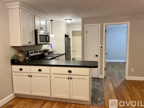 A kitchen with white cabinets and a black countertop.