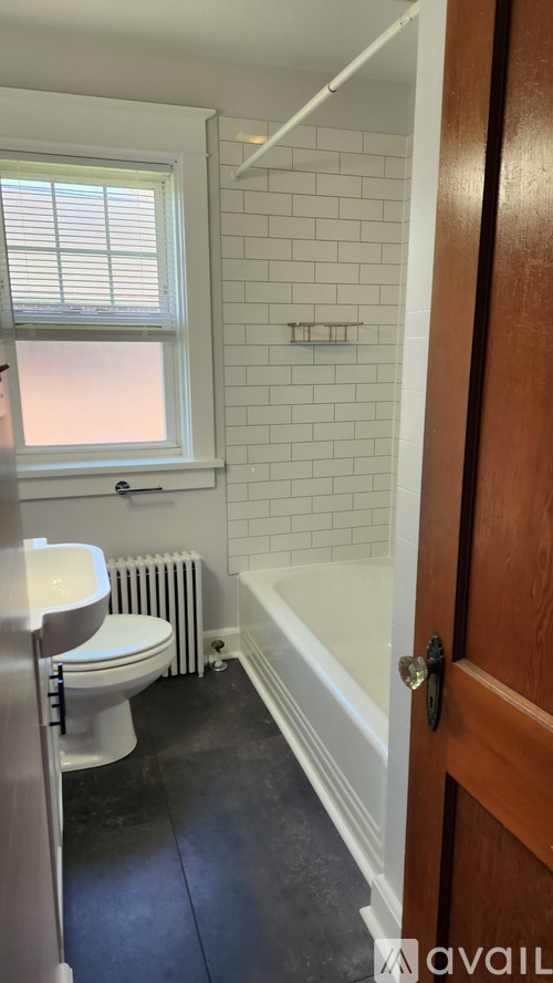 A bathroom with a toilet, a bathtub, and a window.