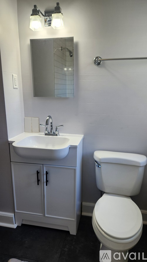 A white toilet sits next to a white sink in a bathroom.