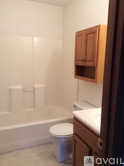 A white toilet sits in a bathroom next to a white bathtub.