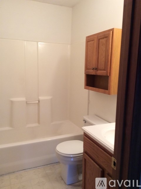 A white toilet sits in a bathroom next to a white bathtub.