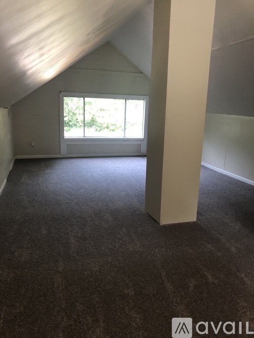 A room with a window and a carpeted floor.