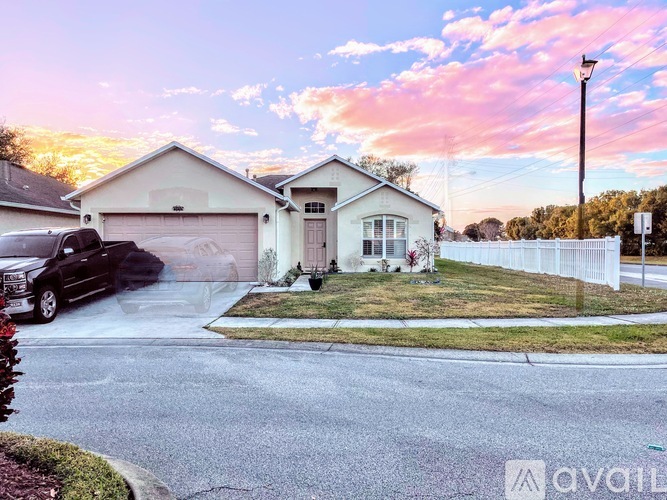 A house with a white fence and a car parked in front.