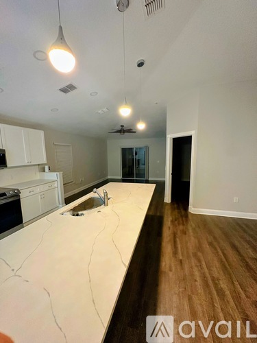 A kitchen with white countertops and wooden floors.