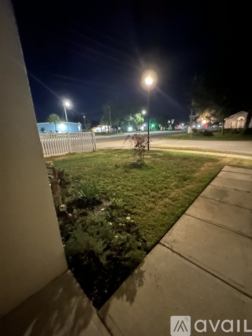 A nighttime scene of a grassy area with a streetlight and a building in the background.