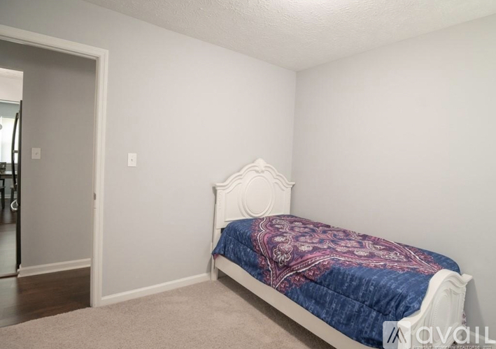 A bedroom with a bed and a carpeted floor.