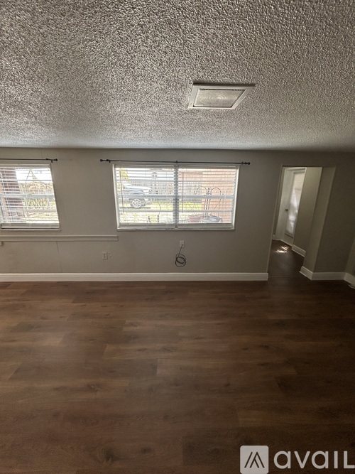 A room with a window and a wooden floor.