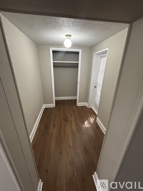 A hallway with wood flooring and white walls.