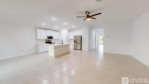 A spacious living room with a kitchen area in the background.